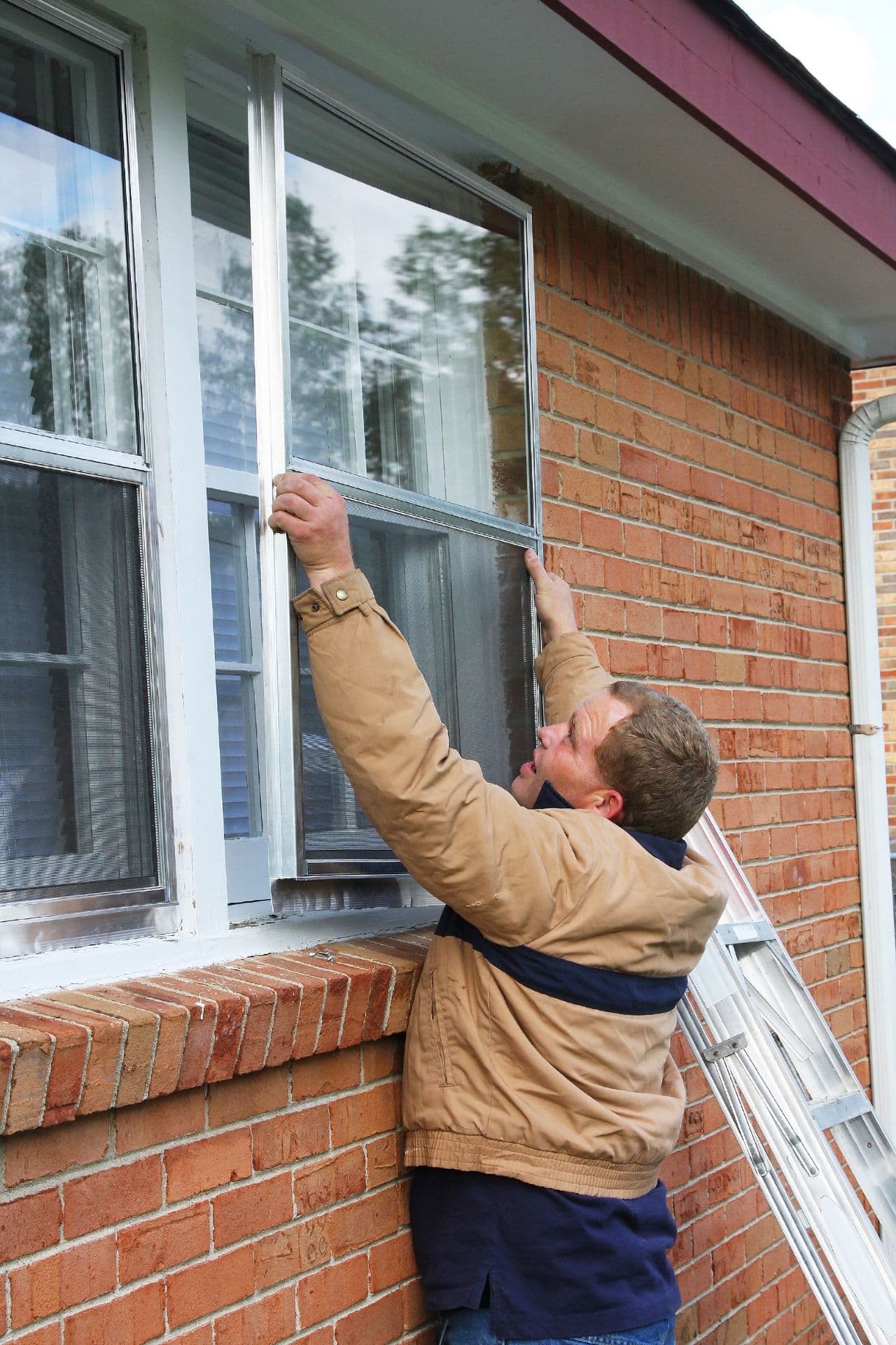 A worker installing new storm windows.