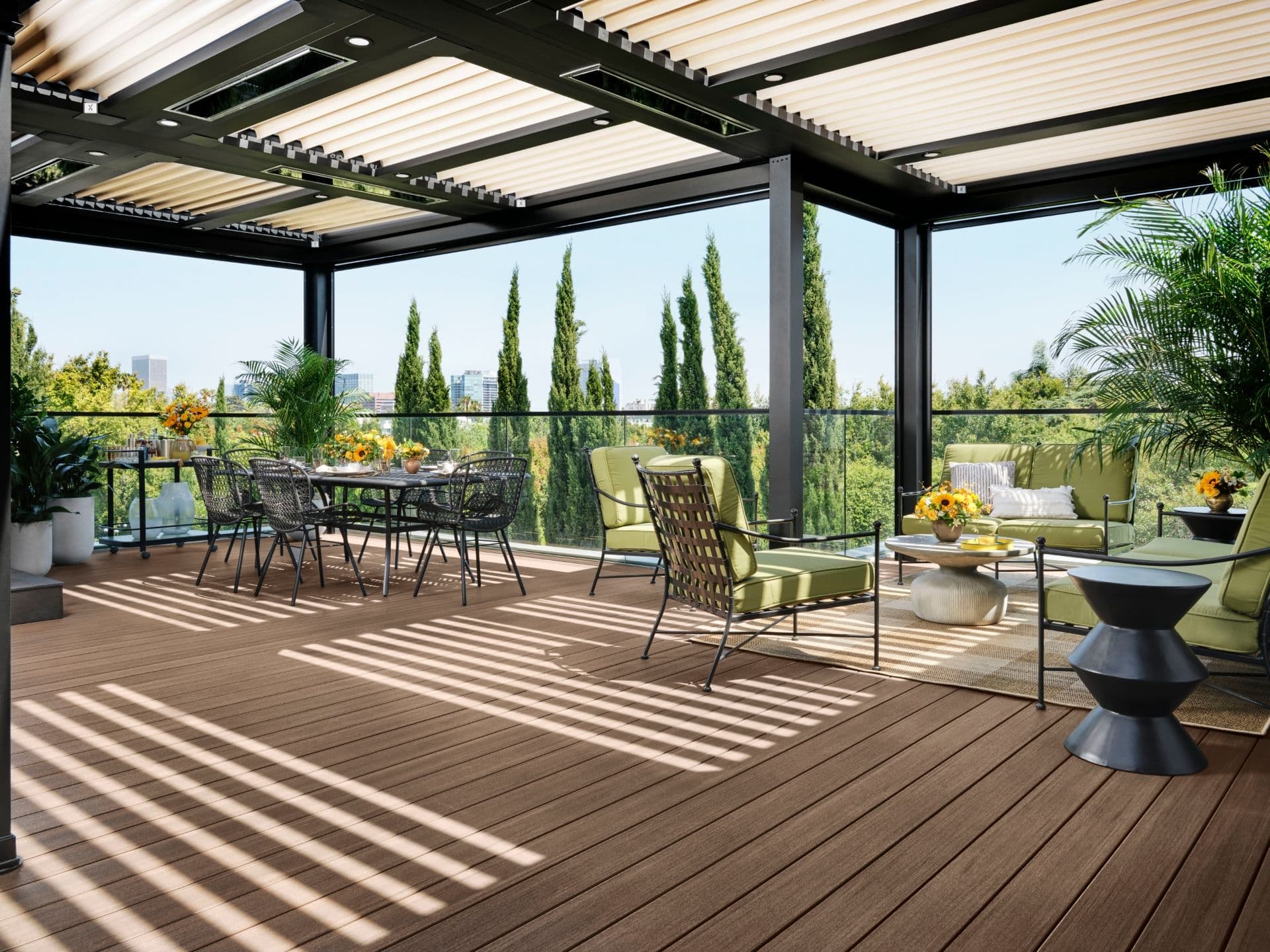 A brown TimberTech deck with a black and white pergola and glass railing.