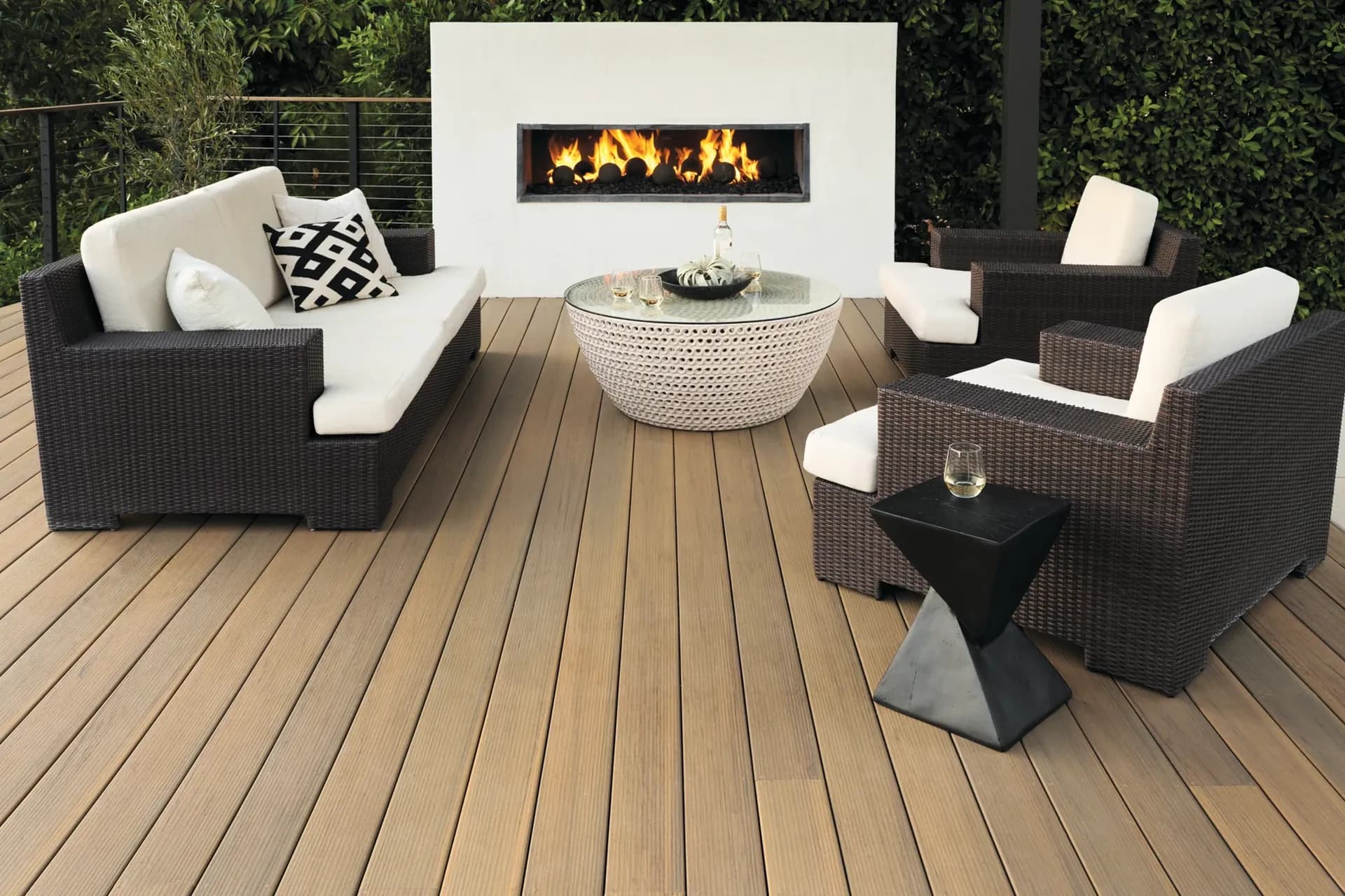 A new light brown TimberTech deck with patio furniture and a fireplace.