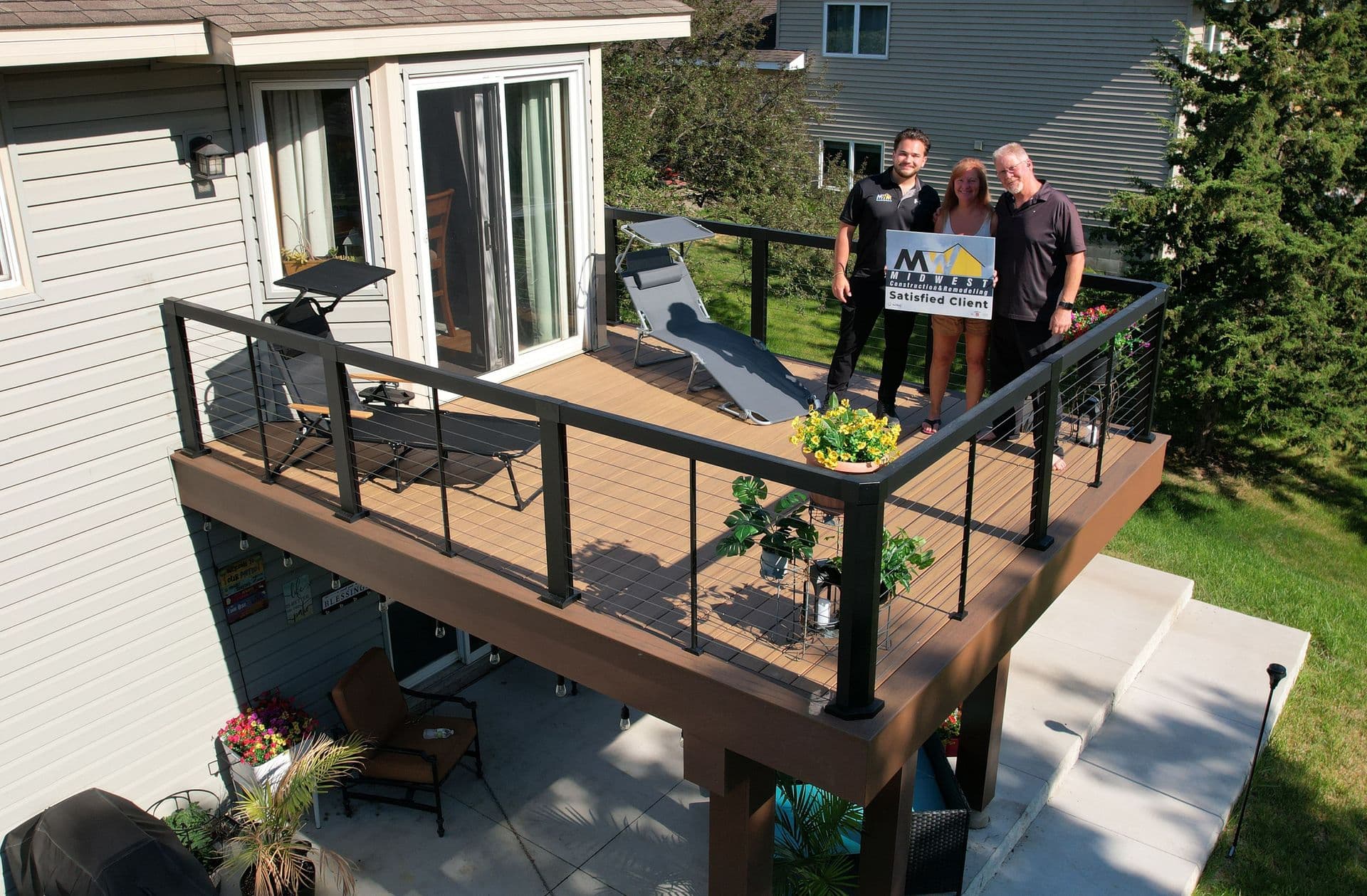 Satisfied clients on their new elevated TimberTech composite deck with cable railing, built by Midwest Construction & Remodeling in Plymouth, MN.