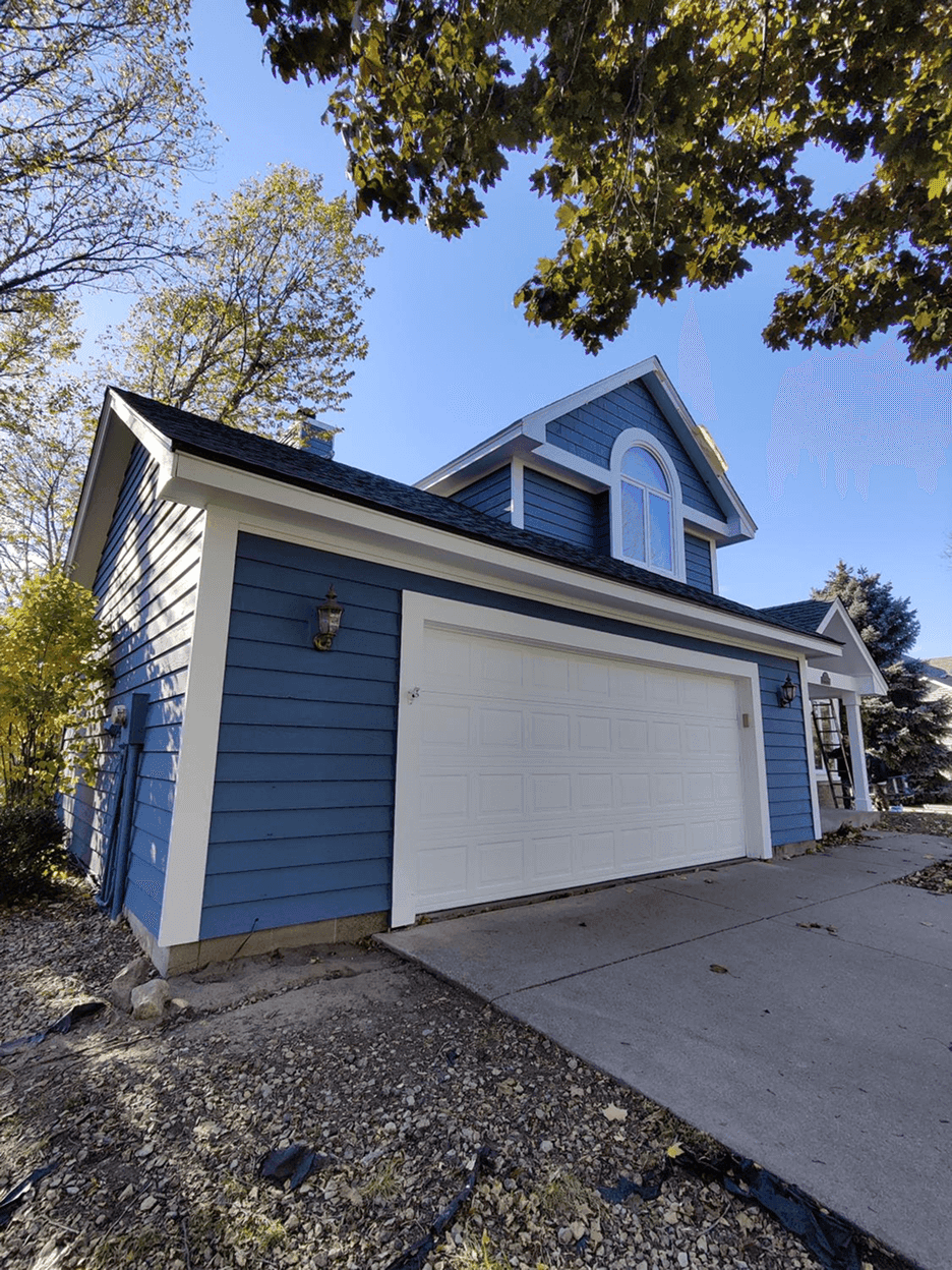 A blue house with white trim and a white garage door.