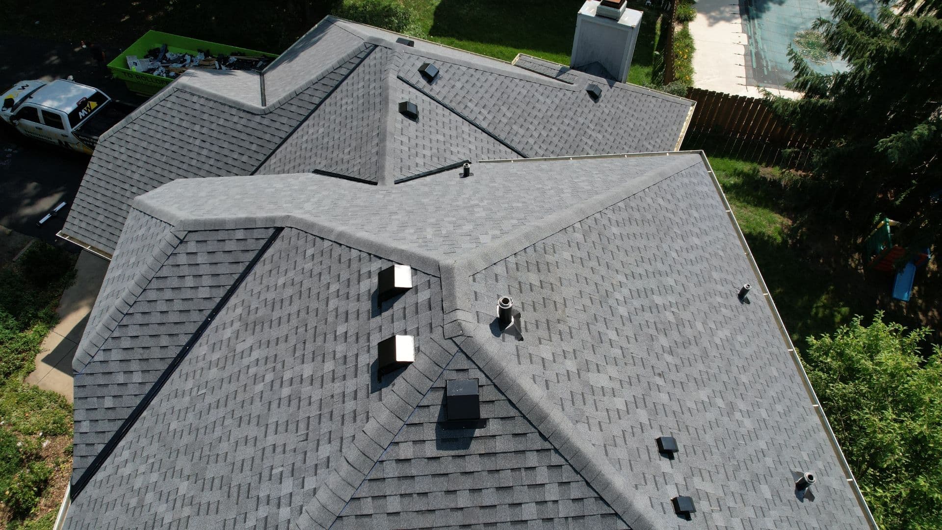 An aerial view of a house with new light gray shingle roofing.
