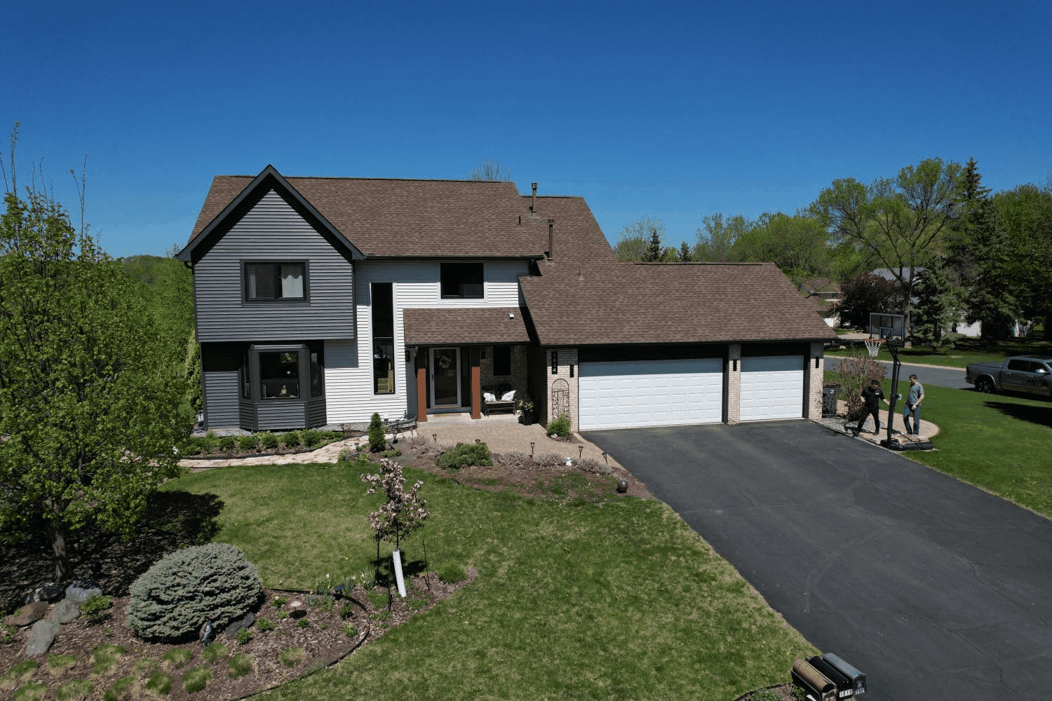 A white and gray house with new brown asphalt shingle roof.