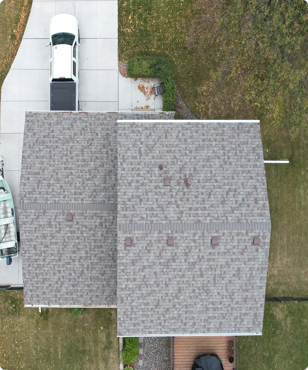 An overhead aerial view of a house with new light gray shingle roofing and a small deck.