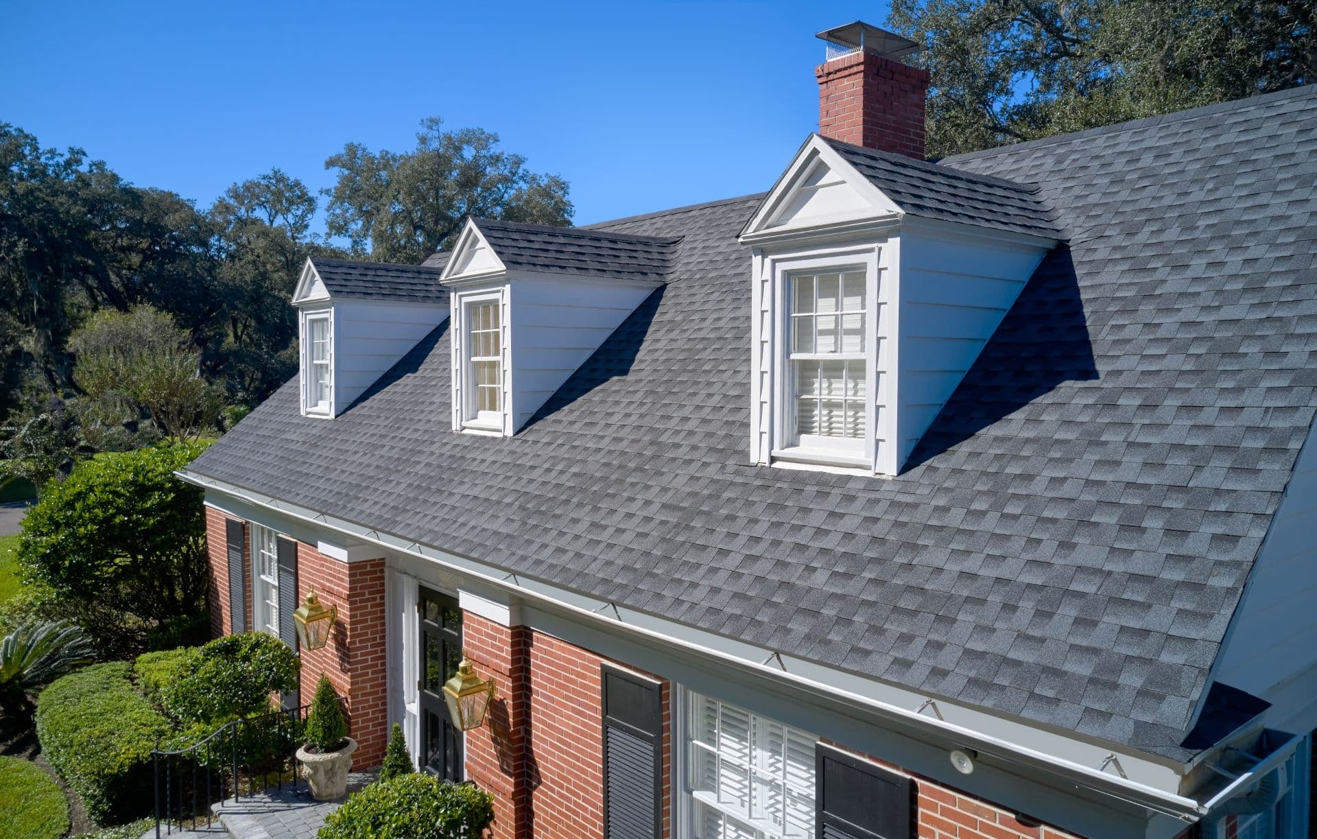 A red brick house with new charcoal gray shingle roof.
