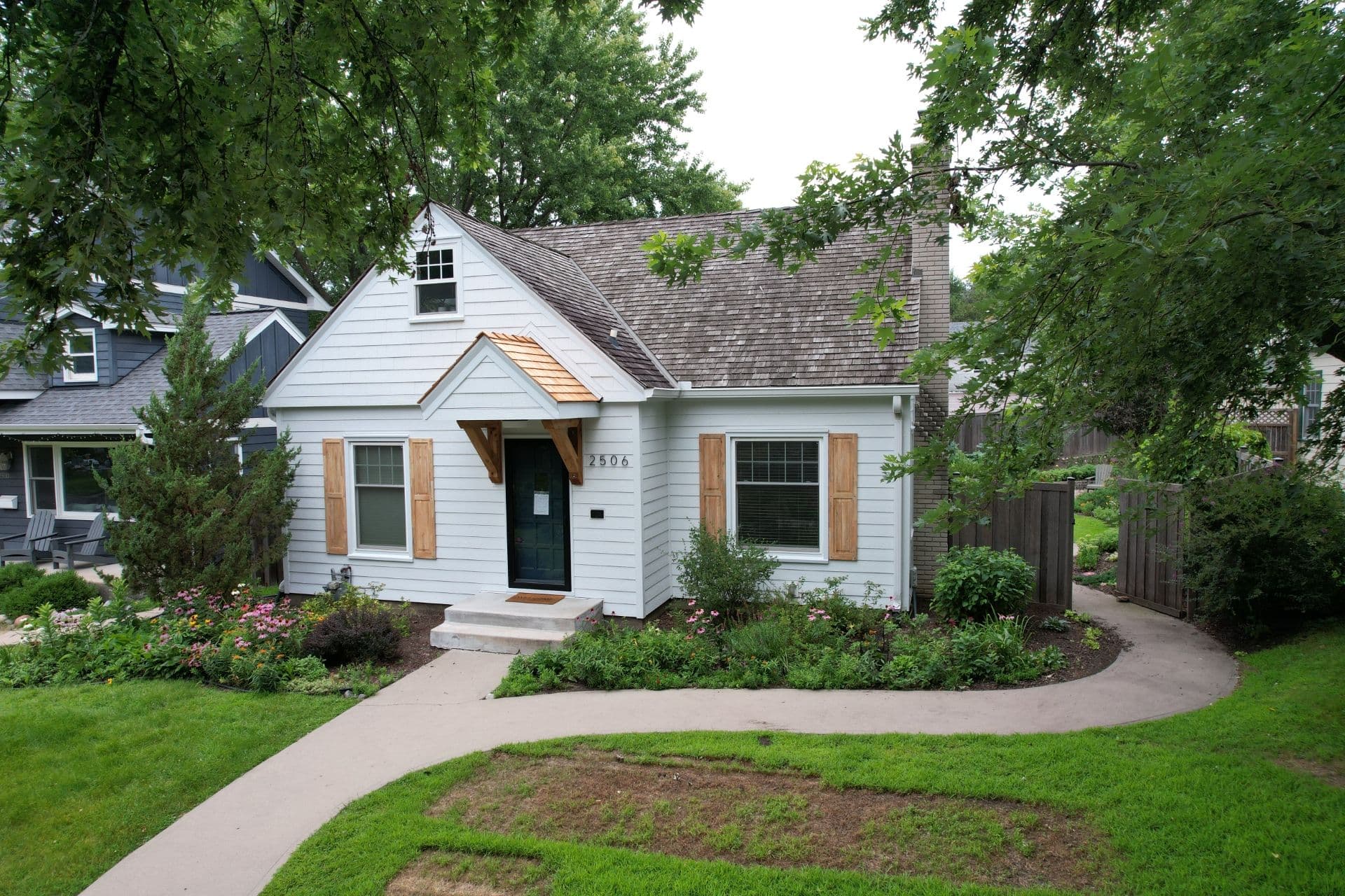 A house with new white siding and natural wood colored shutters.