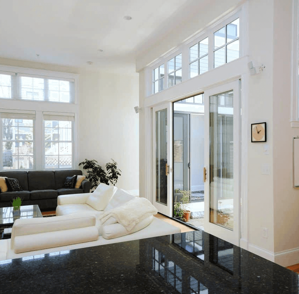 A white living room with black and white couches and sliding glass doors that open to an interior courtyard.