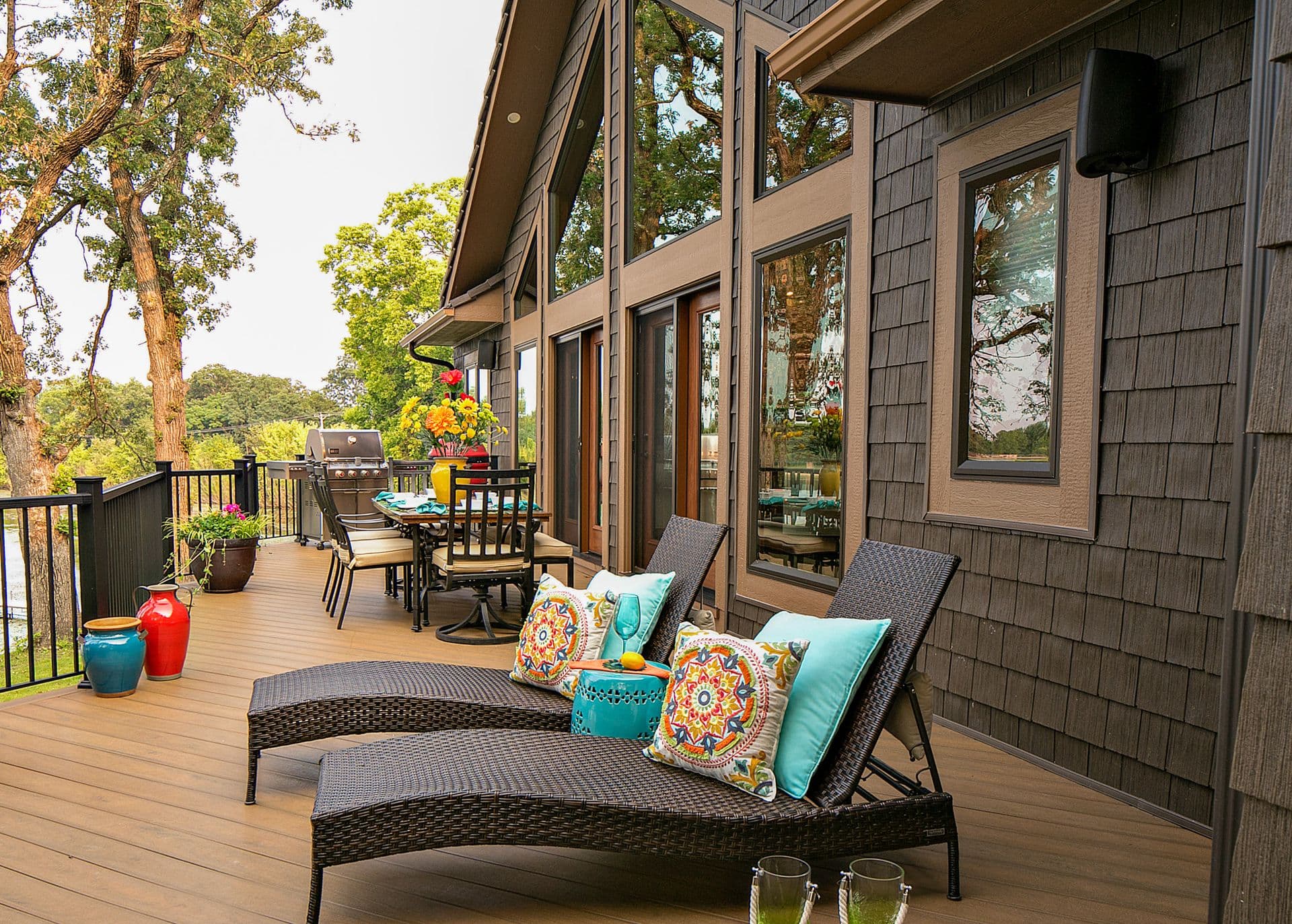 A deck with lounge chairs off of a dark brown house with new ProVia windows.