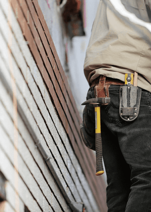 A hammer hangs from a worker's toolbelt.