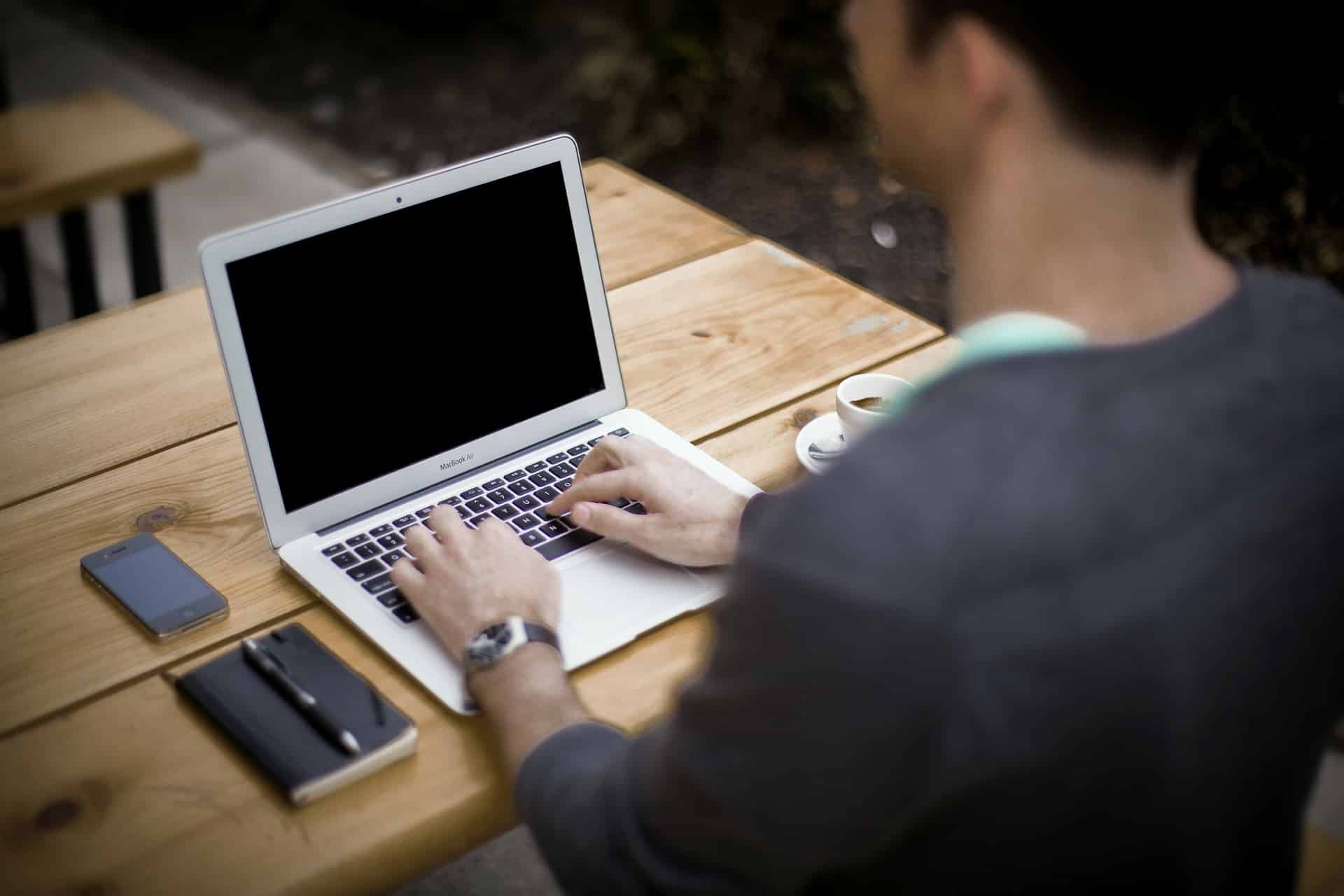 Person working on a laptop at a wooden table
