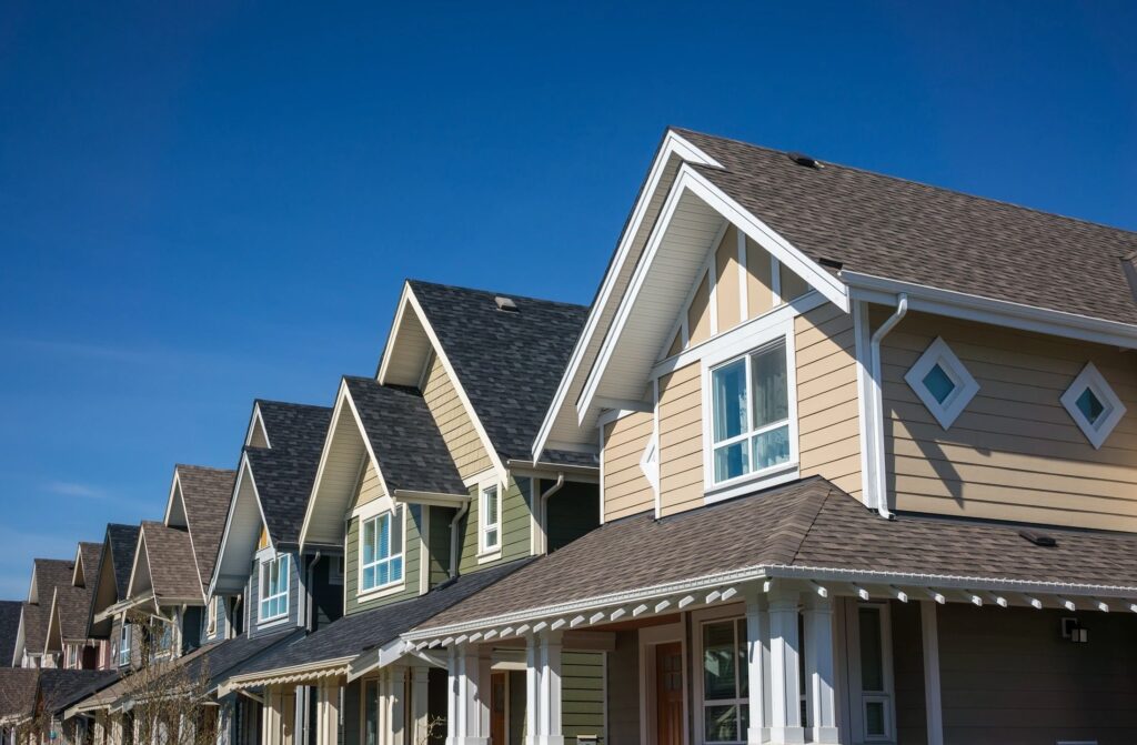 Row of modern suburban homes with gabled roofs against a clear blue sky