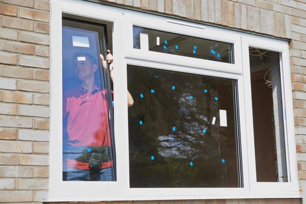 Worker installing new window in a brick house